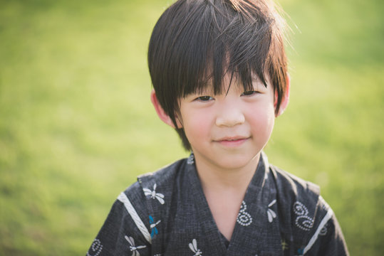 Asian boy in kimono with green field background