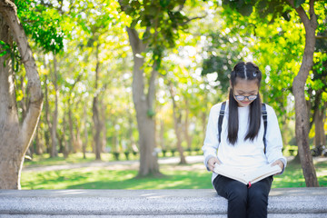 young students enjoys reading a book in garden