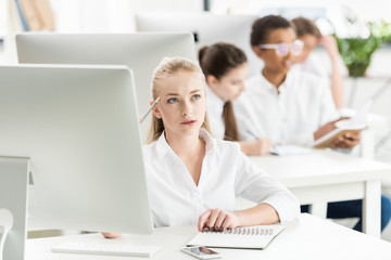 portrait of pensive teenage girl in white shirt studying in classroom