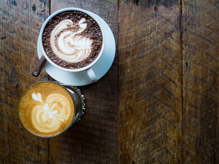 Cups of coffee and hot chocolate show latte art and milk art inspired on old wood table in a coffee shop, top view, copy space 