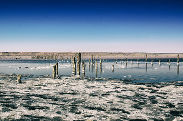 Beautiful salt lake with blue and pink water and wooden posts, natural landscape amazing background