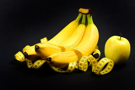 Tape for measuring wrapped around bananas near green apple