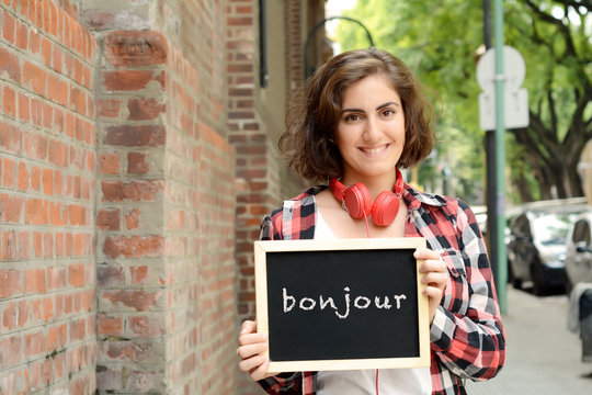 Woman holding chalkboard with "bonjour".
