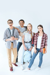 multiethnic group of smiling students with backpacks looking at camera isolated on white