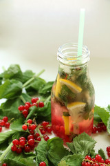 Drink of mint, lemon and red currant in bottle of glass with straw. between in Ingredients