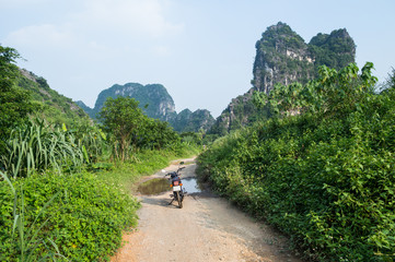 Fototapeta na wymiar Limestone Landscape with Road and Motorbike, Tam Coc, Vietnam