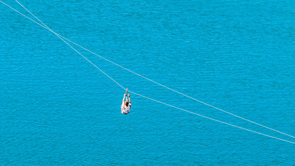 Zipline. The woman in the equipment slides on a steel cable. Trolley Track Over the lake. Extreme...