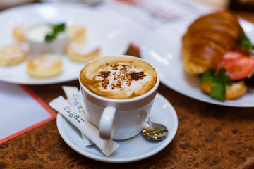 A cup of coffee latte art on top and croissant cheese sandwiches