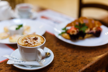 A cup of coffee latte art on top and croissant cheese sandwiches