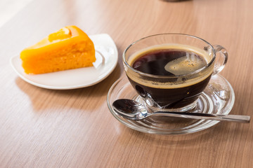 Black coffee and orange cake on wooden table