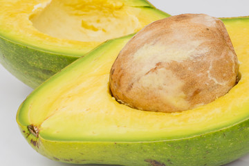 Avocado florida variety rich green ripe cut open with seed pit on white isolated background
