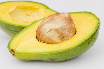Avocado florida variety rich green ripe cut open with seed pit on white isolated background
