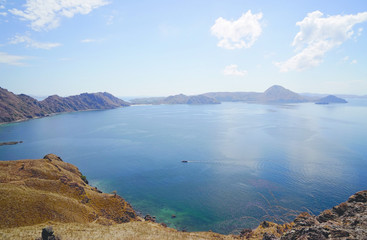 Fototapeta na wymiar Panoramic blue sky view of the hills, mountains and ocean with a small boat from Padar Island part of komodo national park, Flores Indonesia.