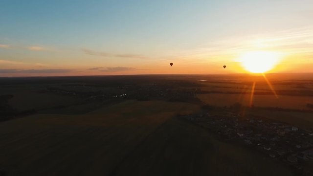 Aerial view Hot air balloon in the sky over a field in the countryside in the beautiful sky and sunset. Balloon silhouette with sunrise, Aerostat fly in the countryside. Aerial footage, 4K