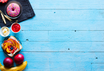 Delicious healthy breakfast, fruit sandwiches with different fillings, cheese, banana, strawberry, fishing, butter, blueberry, on a different wooden background.