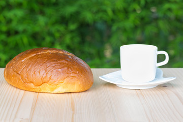 White coffee cup and sliced bread on wooden table