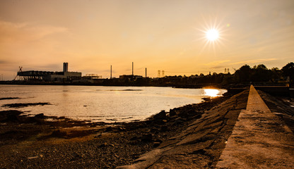 sun above the bay with some industrial buildings in the background
