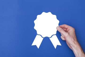 male hand holding a rosette icon symbol against a blue background