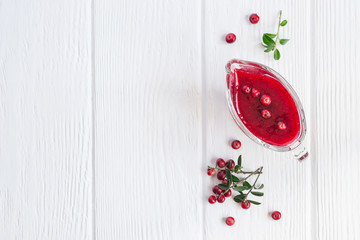 Fresh Lingonberry sauce in a gravy boat On a white wooden background. Top view with copy space