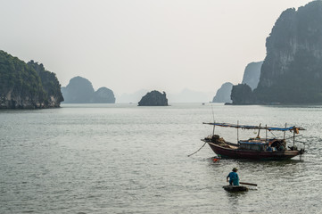 Fototapeta na wymiar Limestone Formations, Fisherman and Boat in the Ocean at Ha Long Bay, Vietnam