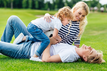 Fototapeta premium happy young parents with cute little son holding soccer ball and having fun at park