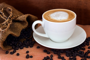 Coffee in a white cup and coffee beans on the table.