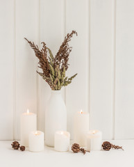 Autumn composition. Spa candles, flowers, pinecone on rustic white wooden background.