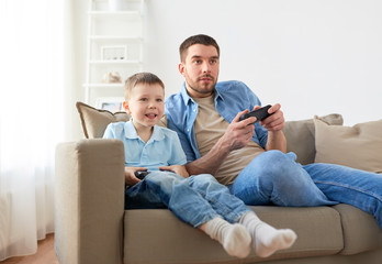 father and son playing video game at home © Syda Productions
