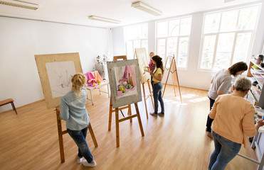 woman artists with brushes painting at art school