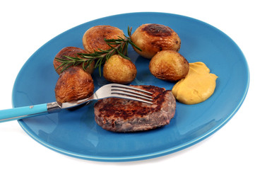 Assiette avec un steak haché, des pommes de terre et de la moutarde sur fond blanc