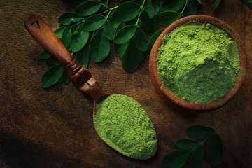 Overhead view of Moringa powder in an earthern pot on dark wooden background