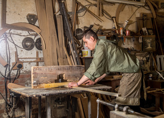 a man works on the machine with the wooden product