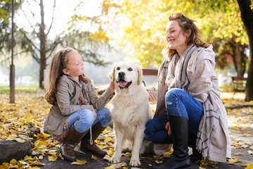 Family woman and her daughter walk autumn park,with his dog golden retriever