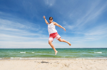 Fototapeta na wymiar smiling young man jumping on summer beach