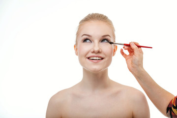 Fototapeta premium Makeup artist applying eye shadow for beautiful young woman on white background