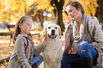 Family woman and her daughter walk autumn park,with his dog golden retriever
