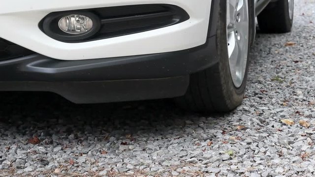 White SUV Pulls out of Rocky Driveway in Summer Time during the Day