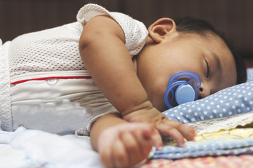 Baby boy sleeping soundly with pacifier.