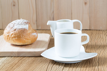 Coffee cup and sourdough roll on wooden table