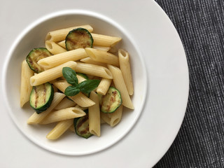 Pasta and grilled zucchini served on white plate. Top view.