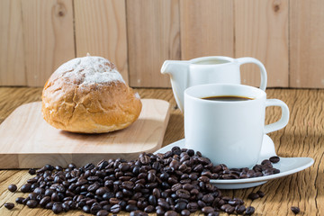Coffee cup and sourdough roll on wooden table