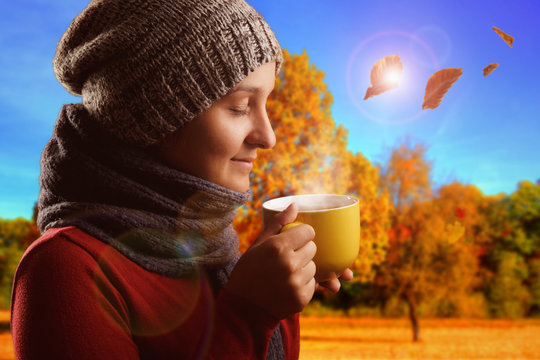 Junge Frau trinkt heissen Tee im Herbst