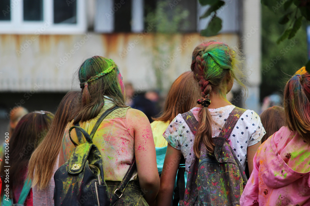 Wall mural Two young girls painted with dry multicolored paints at the festival Holi festival in Gatchina, Russia.