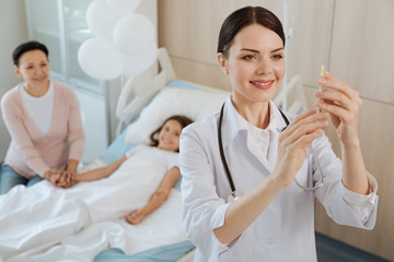 Obraz premium Cheerful positive doctor holding a syringe