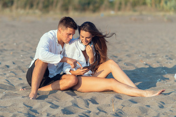 Fototapeta premium Young couple in love using smart phone on the beach 