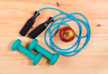 Naklejka premium Dumbbells and skipping rope on wooden background. Top view