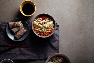Lunch with udon noodles cooked with vegetables and spring rolls. Top view. Composition with copy space