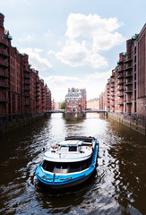 boat on a channel in the old warehouse district Speicherstadt in Hamburg, Germany under blue sky