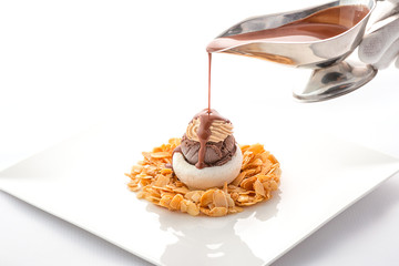 chocolate and nuts ice cream with caramel almond chips and chocolate topping on white plate, exclusive summer dessert, patisserie 