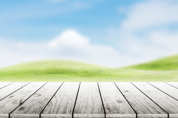 Fototapeta na wymiar Wood table top on blurred mound slope green grass natural background in morning time.